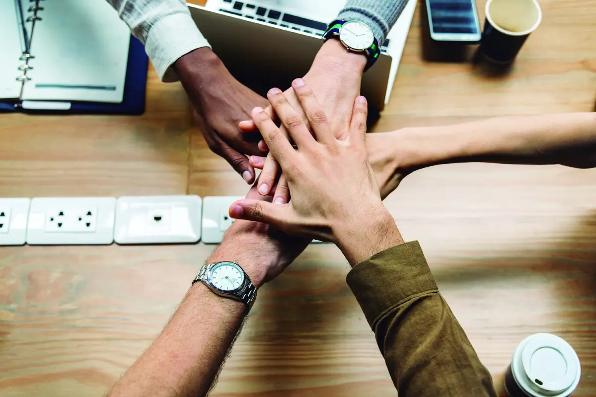 Manos del equipo unidas sobre una mesa de trabajo